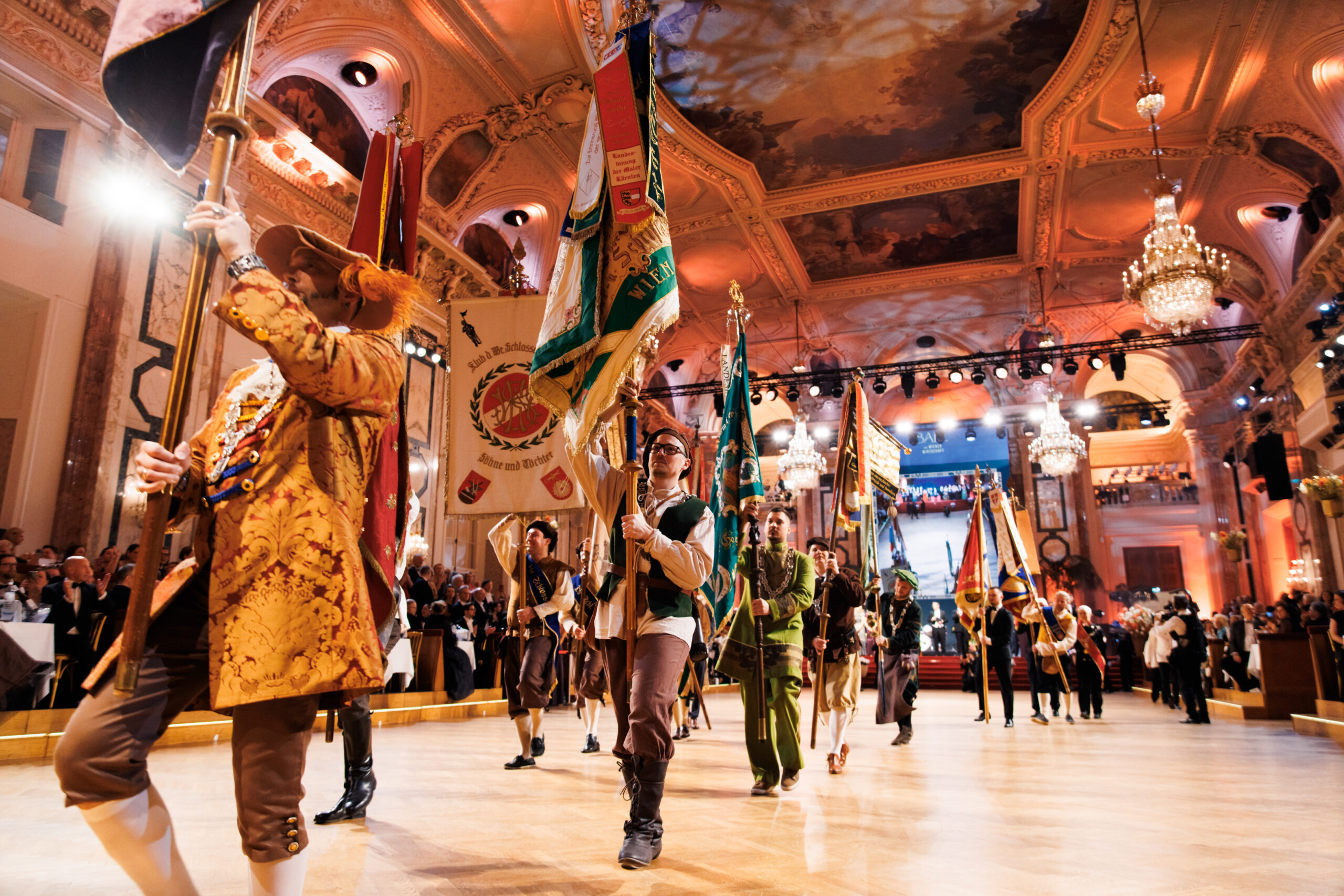 Für dieses Bild würde ich die SEO-Texte wieder passend zur Fahnenparade und Eröffnung gestalten: Alternativtext: Fahnenträger bei der traditionellen Fahnenparade zur Eröffnung des Ball der Wiener Wirtschaft in der Wiener Hofburg